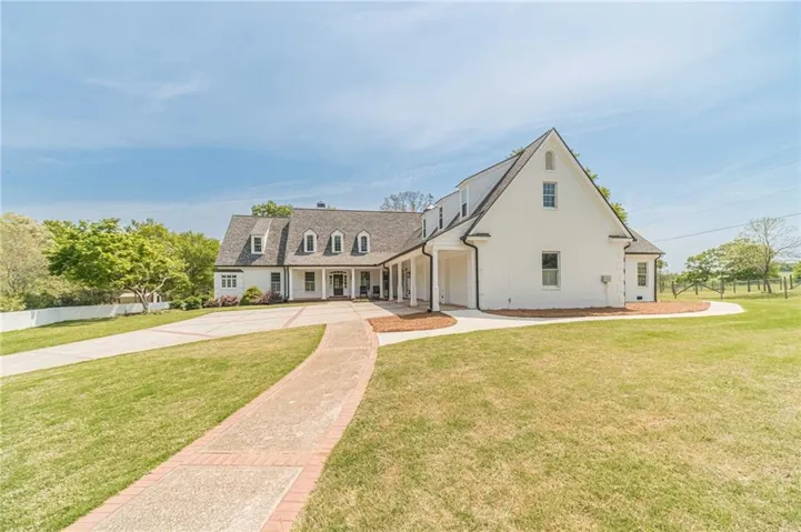 White two-story residence featuring a dark shingled roof and multiple dormer windows