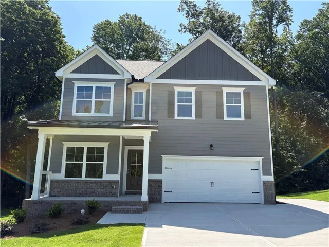Two-story residence featuring a covered front porch, brick accents, and a two-car garage