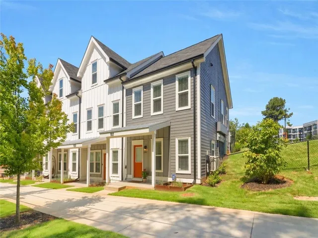 Contemporary townhomes featuring a mix of vertical and horizontal siding, covered front entryways, and vibrant orange front doors
