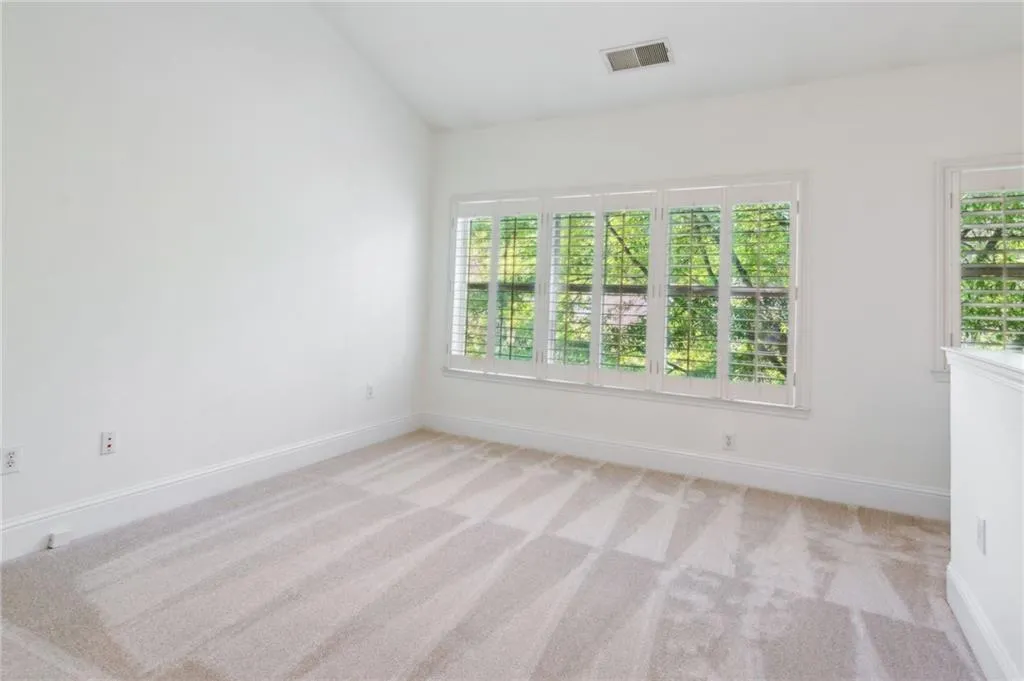Carpeted spare room with lofted ceiling