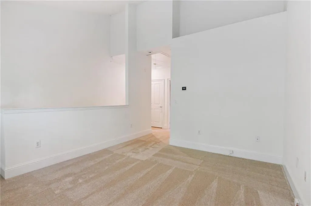 Unfurnished room featuring light colored carpet and a towering ceiling