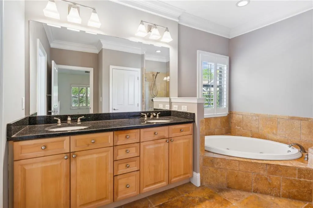 Bathroom with tile flooring, large vanity, double sink, crown molding, and tiled bath