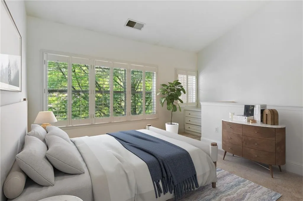 Bedroom featuring light colored carpet and multiple windows