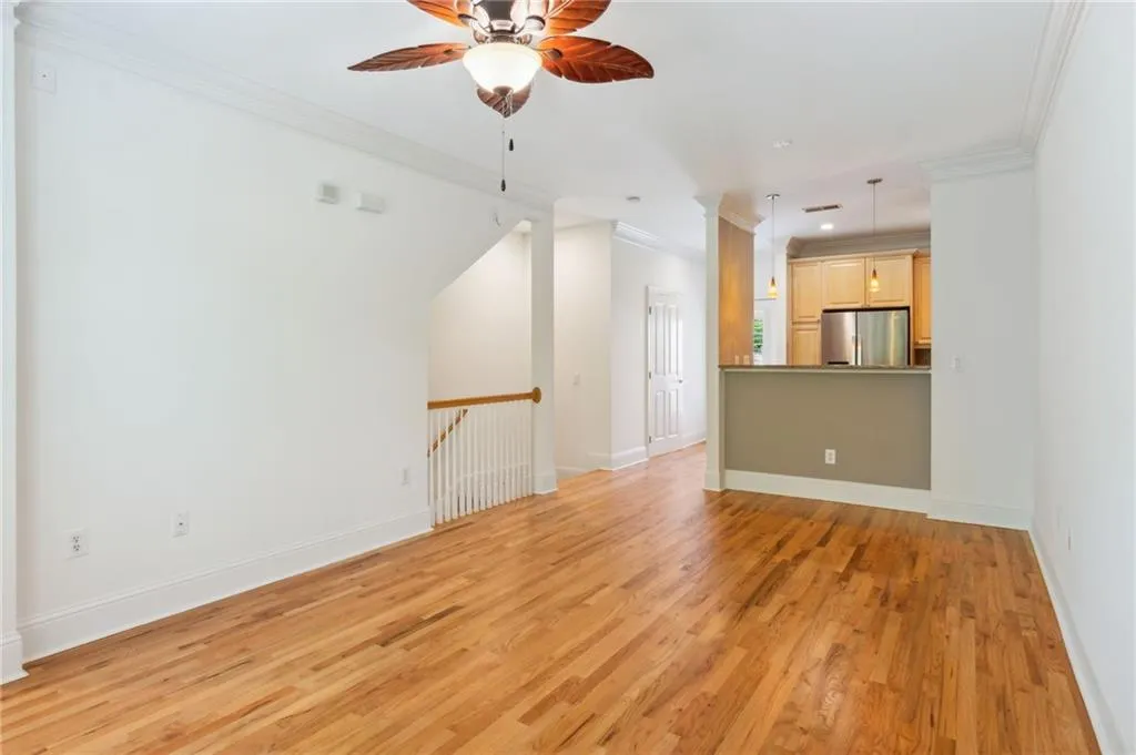 Unfurnished living room with ceiling fan, light wood-type flooring, and ornamental molding