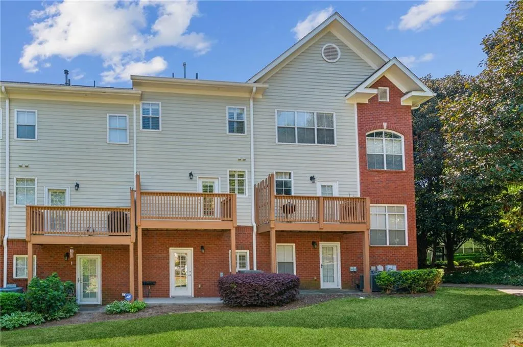 Back of house featuring a balcony and a lawn