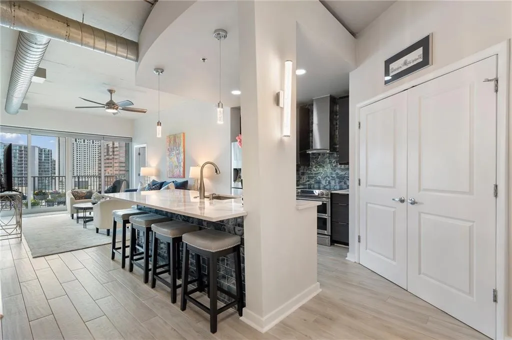 Kitchen featuring a breakfast bar, double oven range, backsplash, open floor plan, and wall chimney range hood