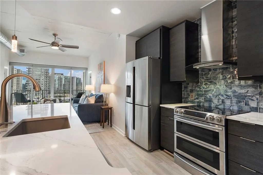 Kitchen with wall chimney range hood, a sink, appliances with stainless steel finishes, a view of city, and dark cabinets