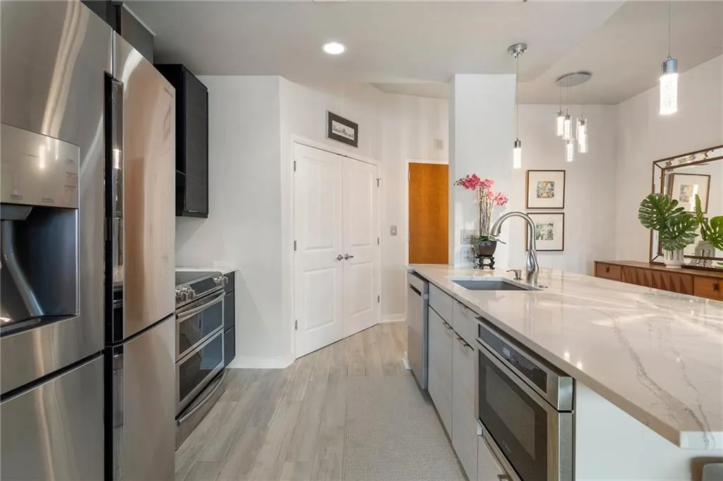 Kitchen featuring light stone countertops, a sink, stainless steel appliances, light wood-style floors, and modern cabinets