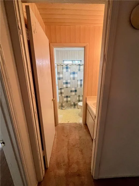Bathroom with vanity, curtained shower, and wooden walls
