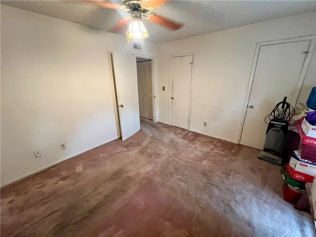 Unfurnished bedroom featuring multiple closets, carpet floors, and ceiling fan
