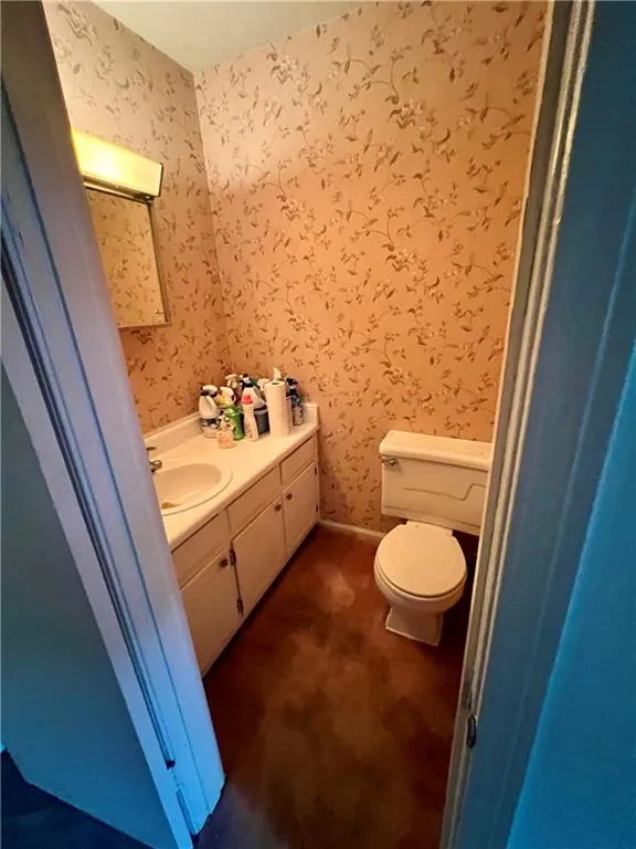 Half bathroom featuring vanity and wallpapered walls