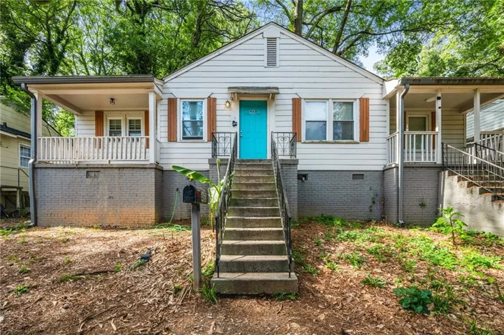 View of front of home with stairs, a porch, and crawl space