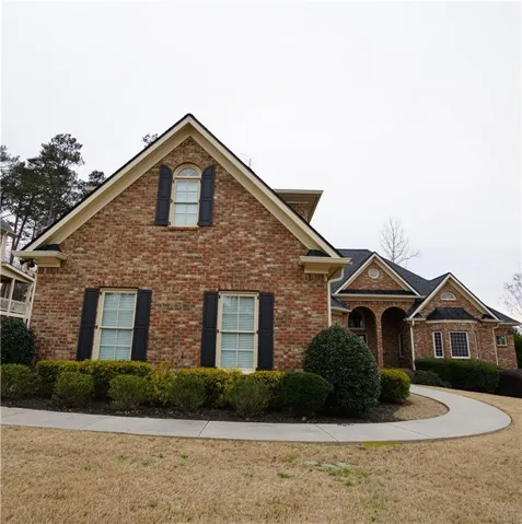 Brick exterior with dark shutters, gabled rooflines, and arched entry