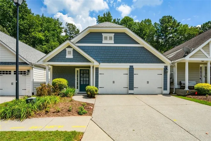 Exterior featuring blue siding, white trim, a two-car garage, an inviting entryway, and a landscaped front garden