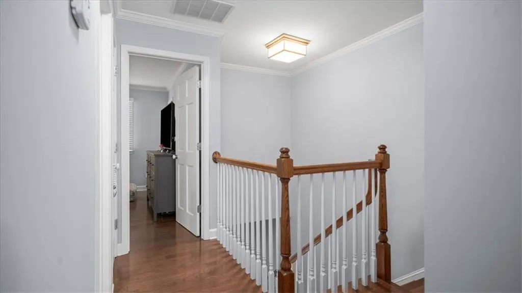 Hallway with crown molding and dark wood-type flooring