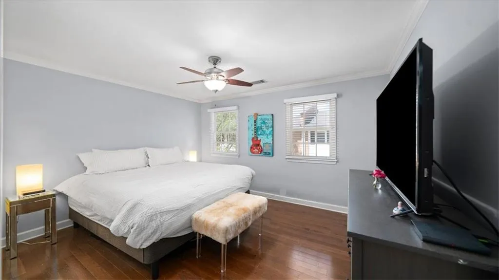 Bedroom with dark hardwood / wood-style flooring, ceiling fan, and ornamental molding