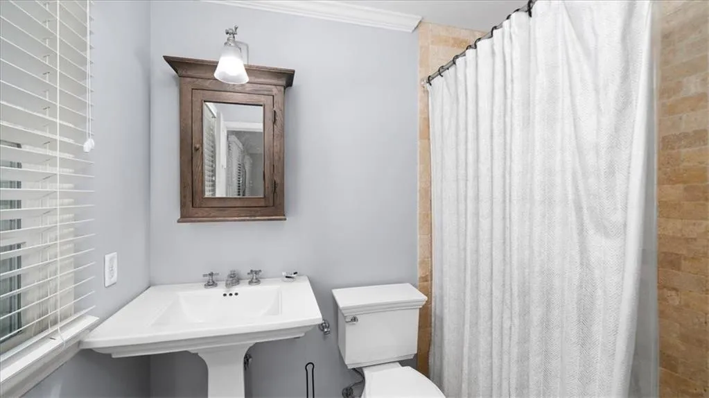 Bathroom featuring toilet, ornamental molding, and sink