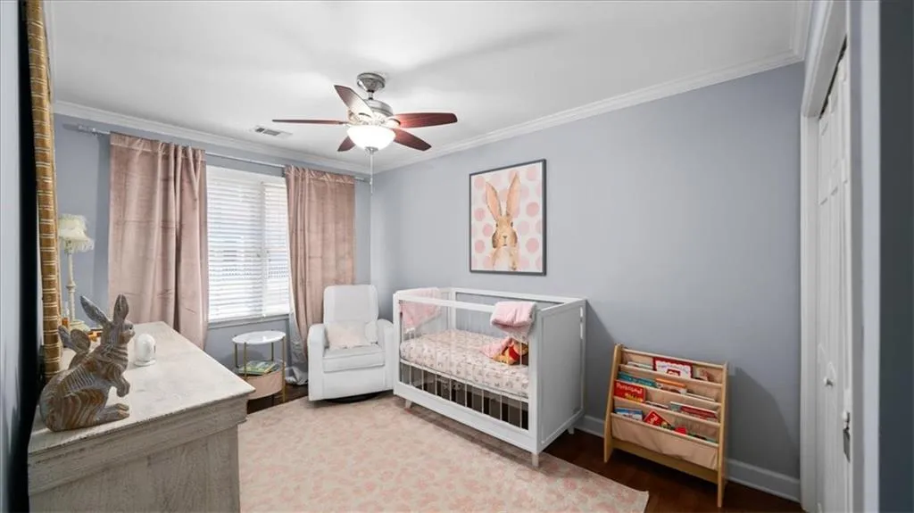 Bedroom featuring hardwood / wood-style floors, a closet, ceiling fan, and crown molding