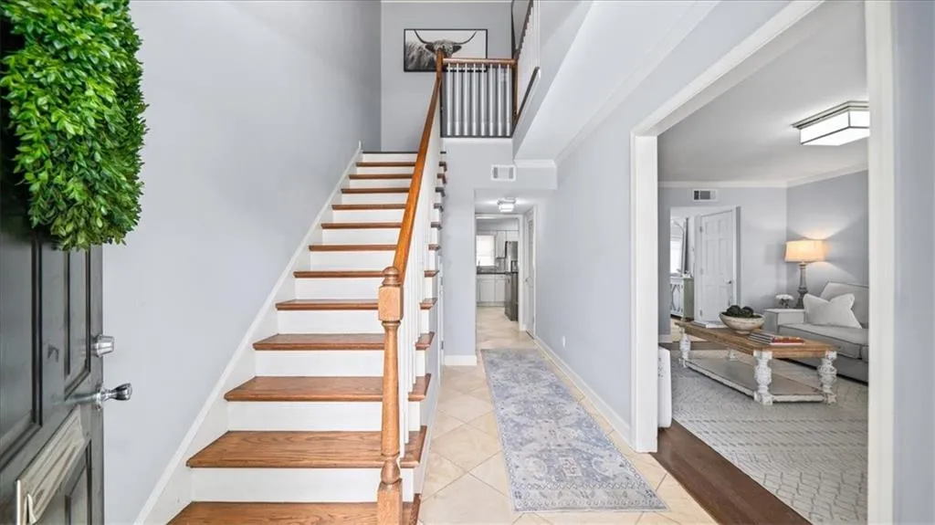 Stairway with crown molding, a towering ceiling, and light hardwood / wood-style floors