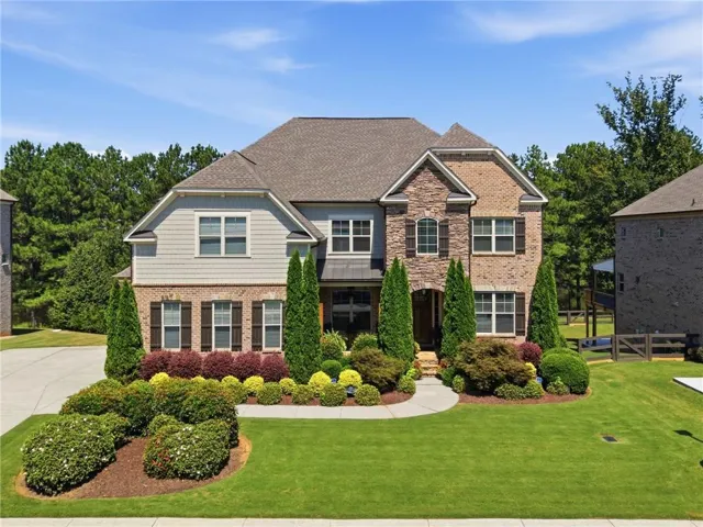 Brick and siding facade with dark shutters, gabled roofline, and front landscaping