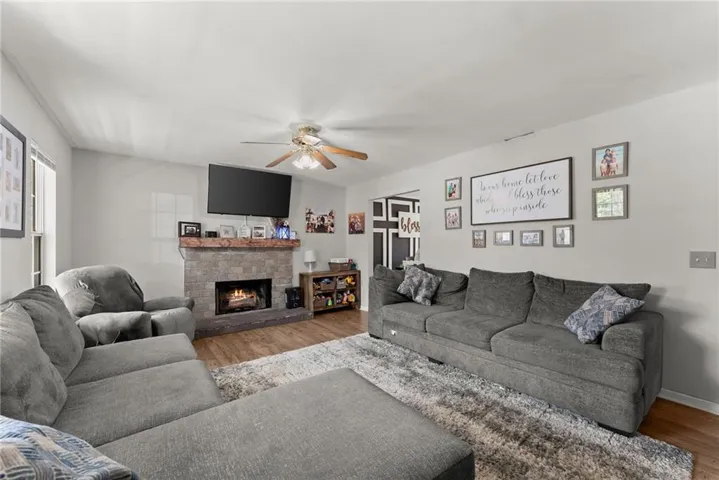 Living room featuring wood finished floors, ceiling fan, and a fireplace
