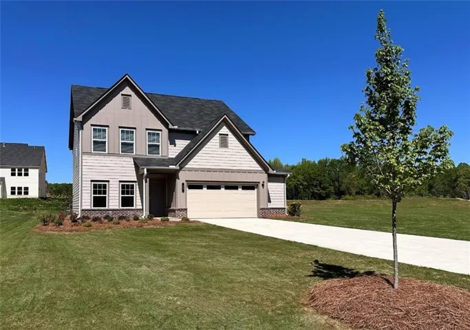 View of front of property with board and batten siding, concrete driveway, a front yard, and a garage
