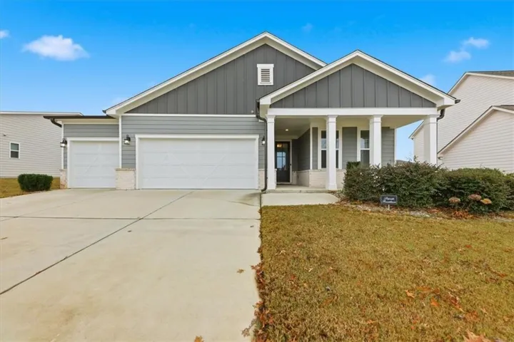 View of front of house featuring board and batten siding, a porch, an attached garage, brick siding, and concrete driveway
