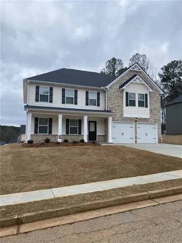 View of front facade with a garage, a porch, and a front lawn