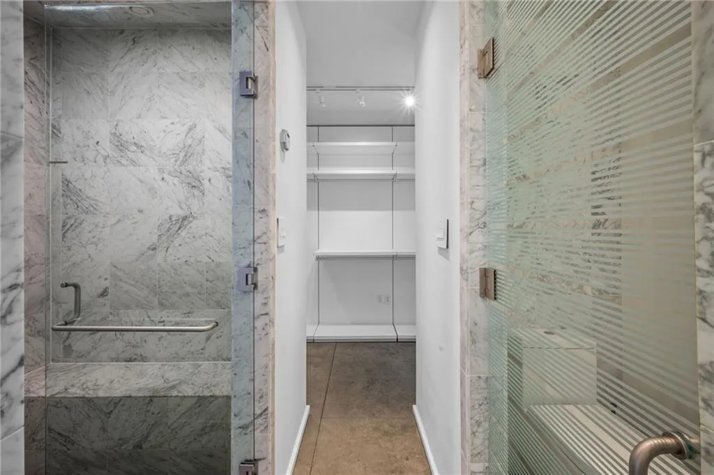 Full bathroom featuring a marble finish shower, a walk in closet, and light tile patterned floors