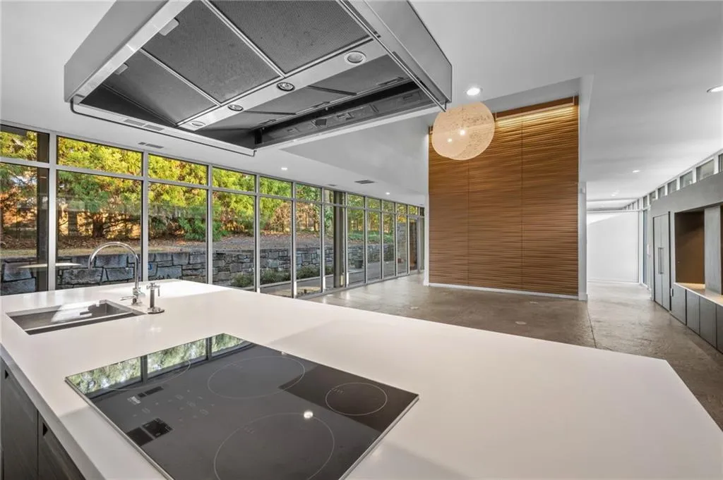 Kitchen featuring range hood, black electric cooktop, brown cabinets, expansive windows, and recessed lighting