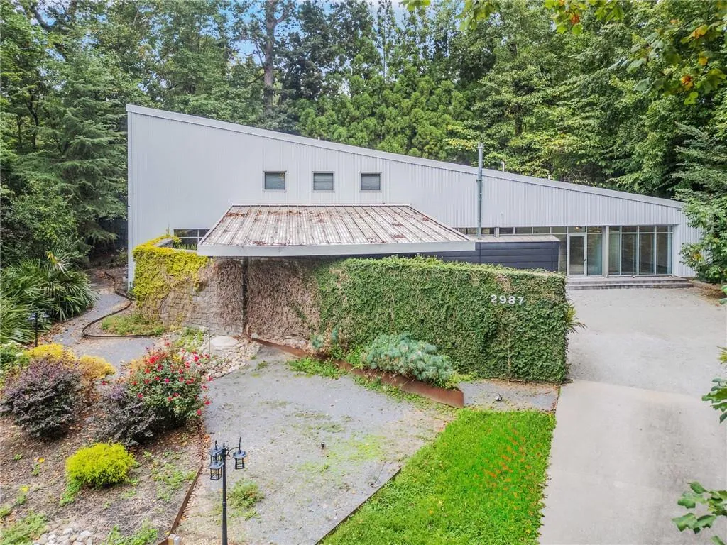 View of front of property featuring lawncare items and a metal roof