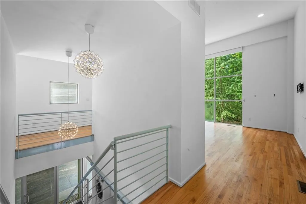 Hallway with a chandelier, healthy amount of natural light, an upstairs landing, and wood finished floors