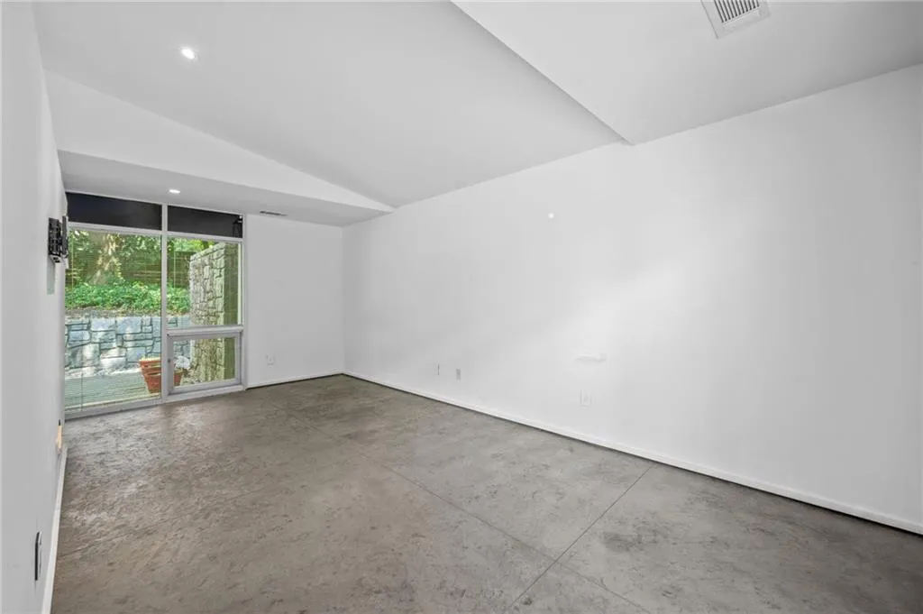 Empty room featuring vaulted ceiling, concrete floors, and recessed lighting