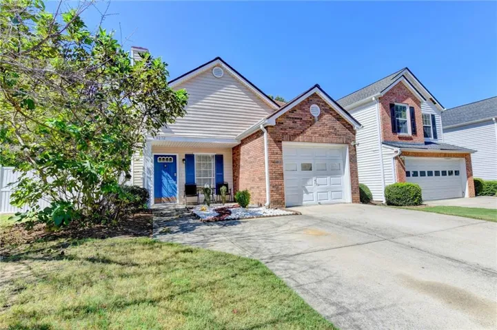 Brick and siding exterior, attached garage, blue front door, blue window shutters, and white picket fence