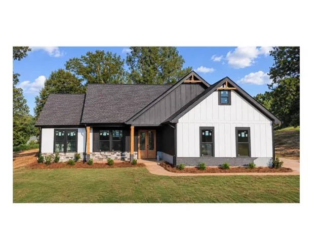 Modern farmhouse exterior featuring dark gray vertical siding, white board and batten accents, a stone veneer foundation, and a dark shingle roof