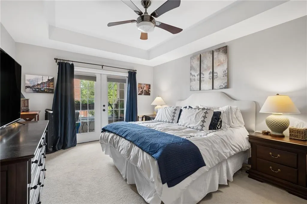 Primary bedroom with tray ceiling and french doors leading out to patio.