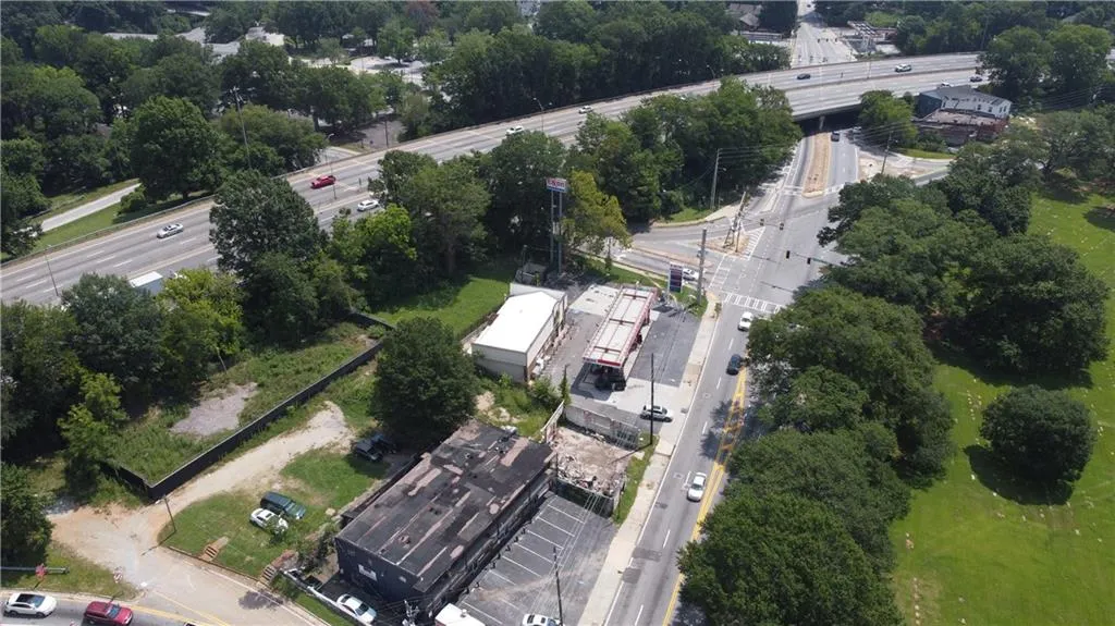 Aerial view of property and surrounding area with a main thoroughfare and a tree filled landscape