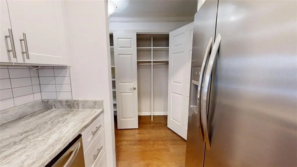 Kitchen with stainless steel appliances, white cabinets, tasteful backsplash, light wood-style flooring, and crown molding
