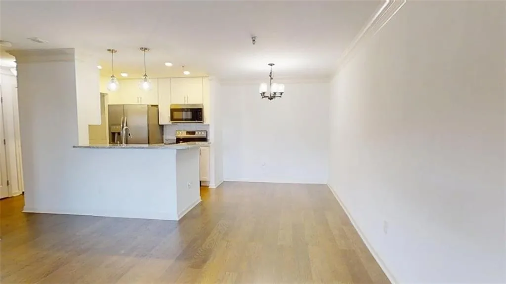 Kitchen with decorative backsplash, a chandelier, hanging light fixtures, light wood-style floors, and ornamental molding