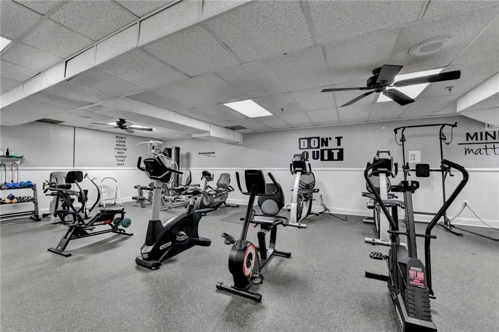 Workout area with ceiling fan, a drop ceiling, and wainscoting
