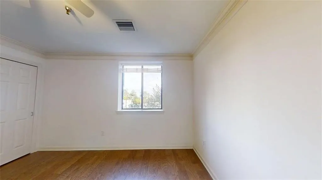 Unfurnished bedroom with crown molding, wood finished floors, and ceiling fan