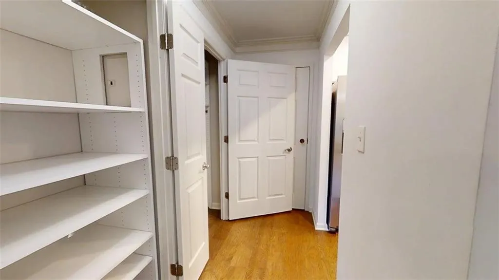 Hallway featuring light wood-type flooring and ornamental molding