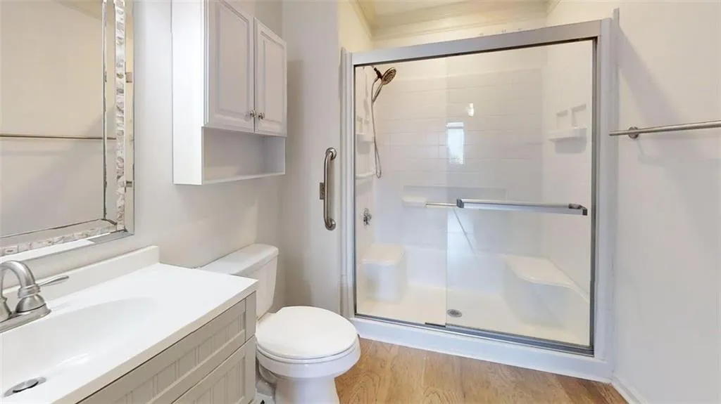 Full bath featuring a stall shower, light wood-style floors, vanity, and ornamental molding