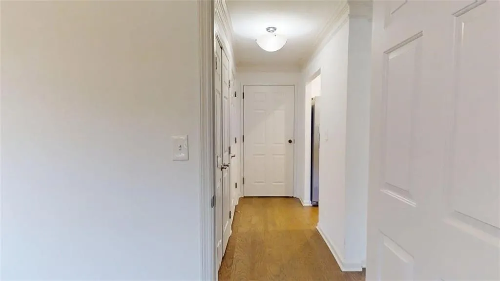 Hall with light wood-type flooring and crown molding