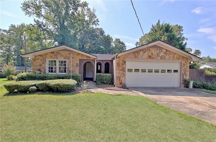 Stone veneer exterior with a gabled roofline and attached garage featuring a white door with transom-style windows
