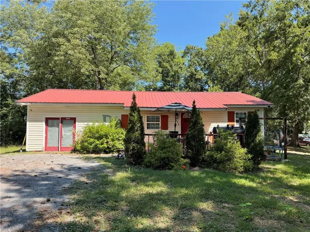 Vinyl siding exterior with a red metal roof