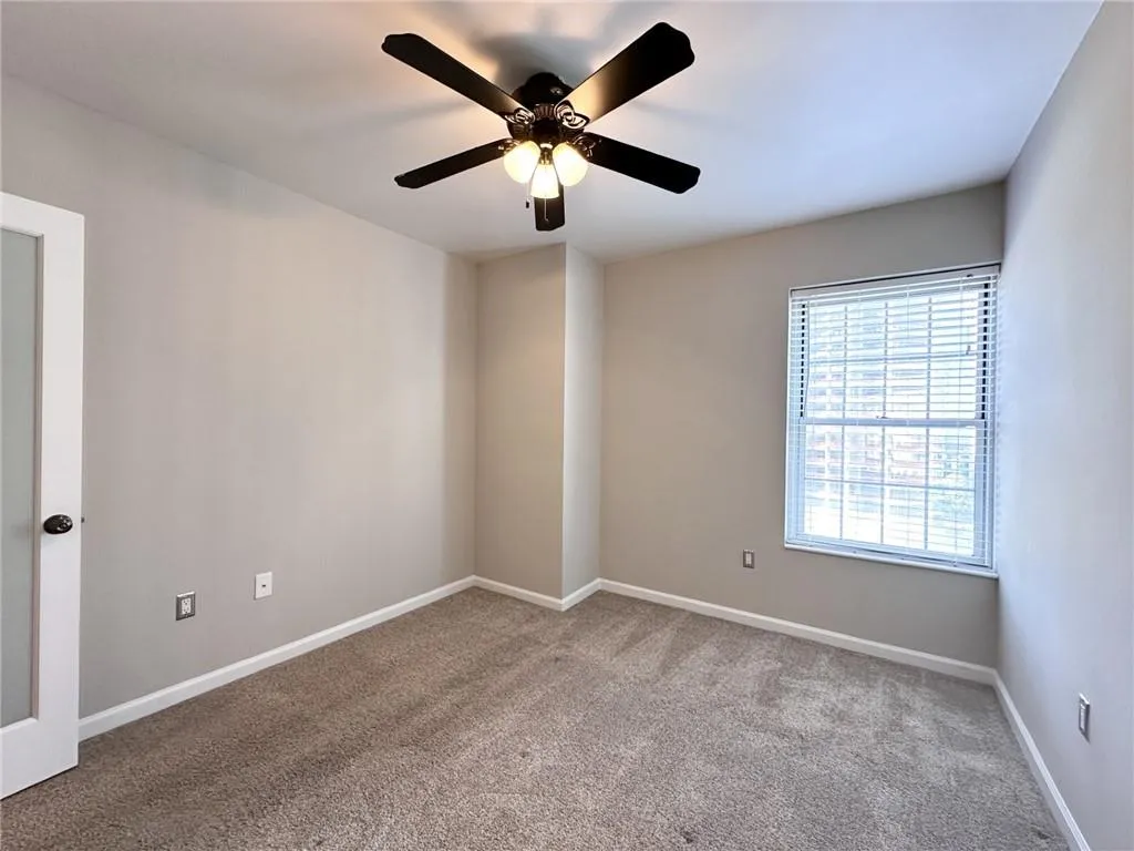 Empty room featuring carpet flooring and ceiling fan
