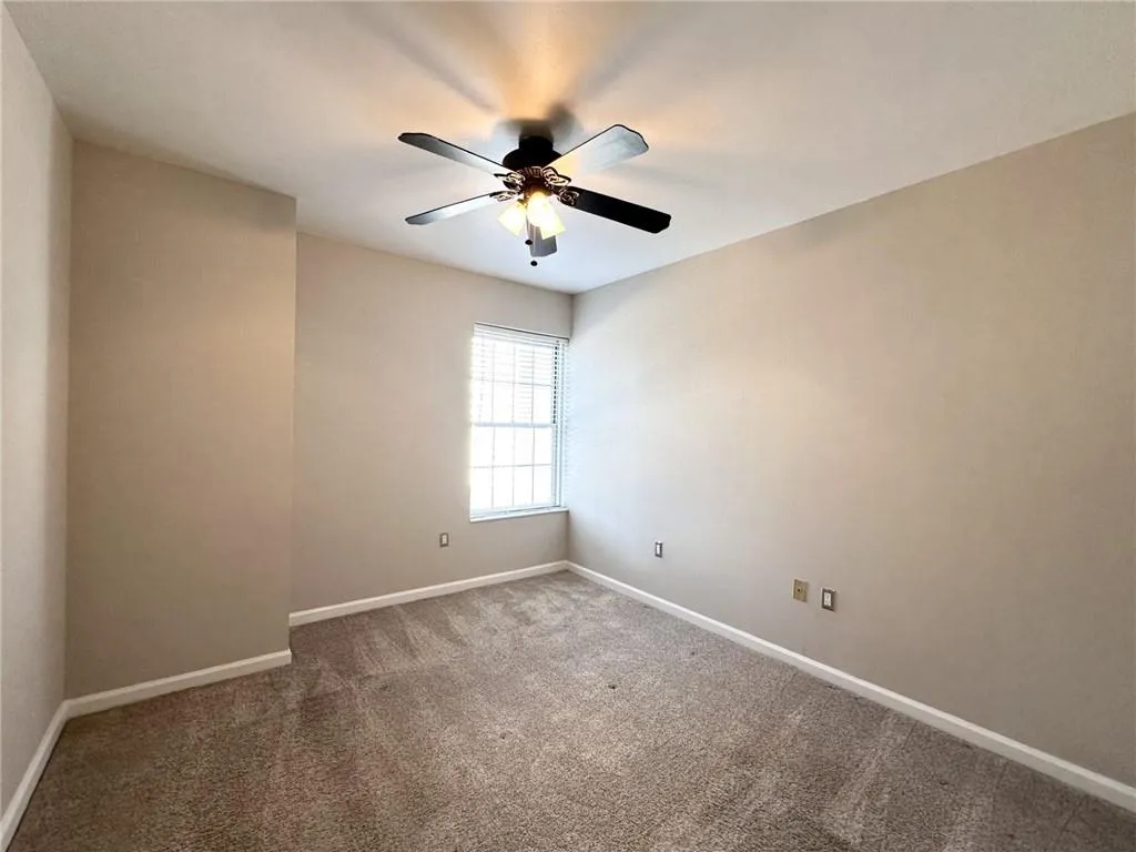 Spare room featuring carpet and ceiling fan