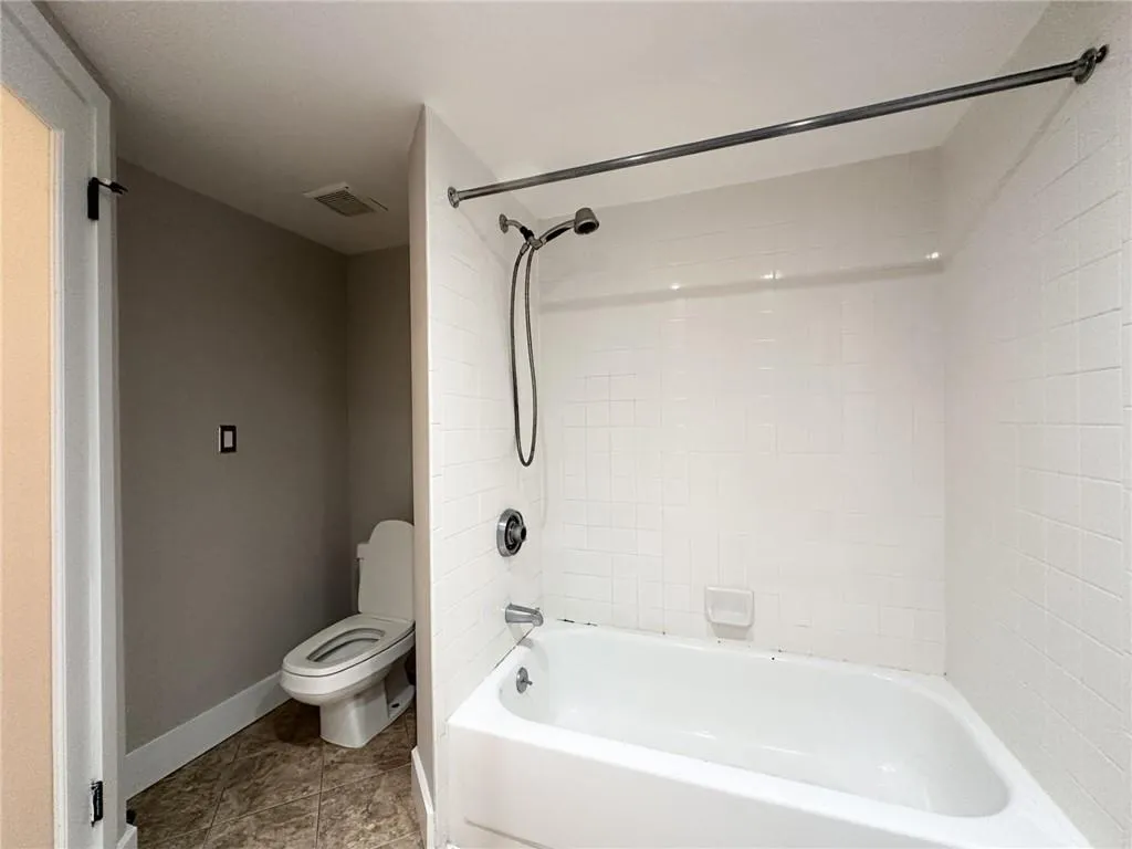 Bathroom featuring washtub / shower combination and light tile patterned floors