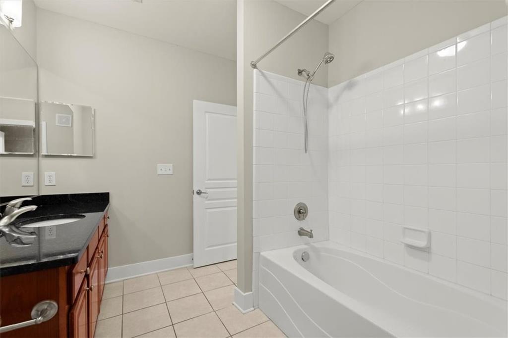 Bathroom with tiled shower / bath, vanity with extensive cabinet space, and tile flooring